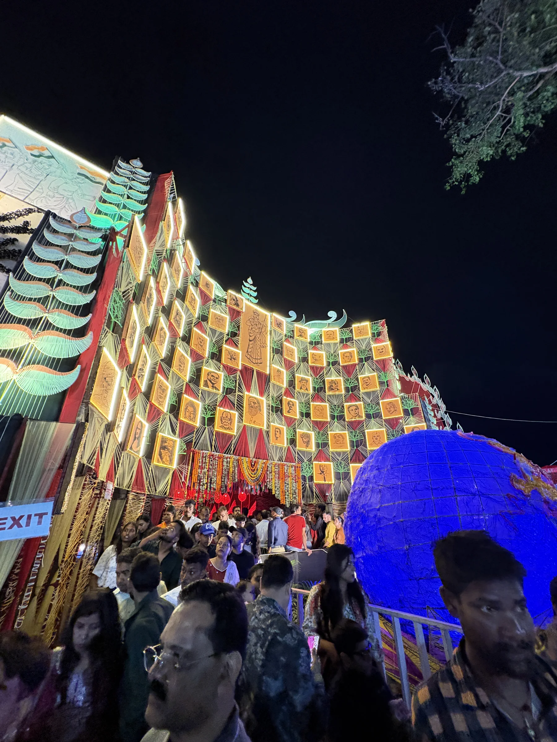 A brightly illuminated pandal facade at night