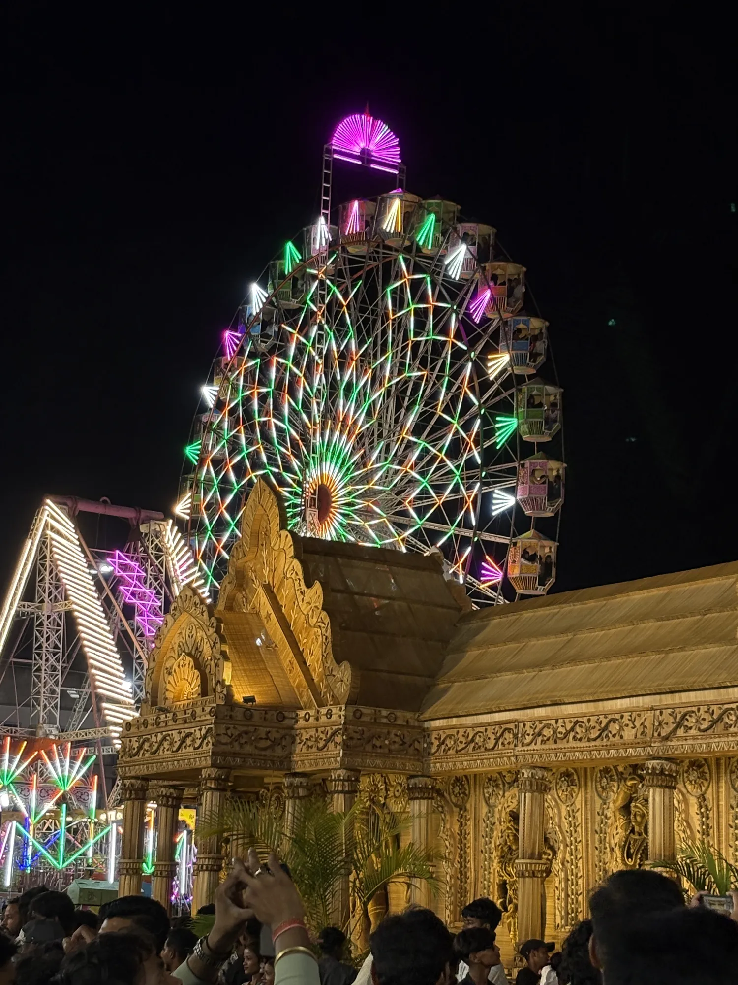 Colourful Ferris wheel rising above the festival at night